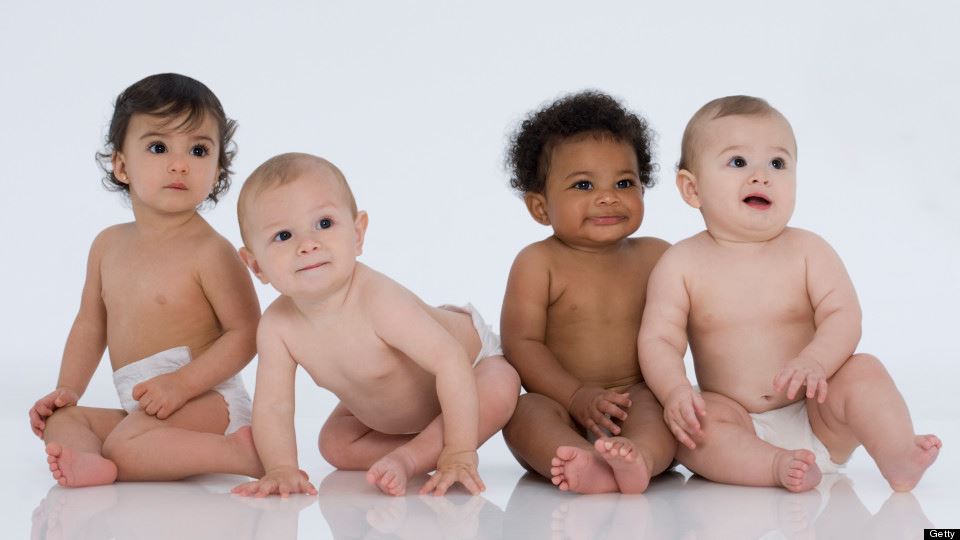 Photo of babies with several different skin colors sitting in diapers